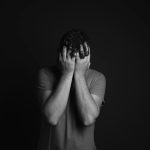 gray scale photo of man covering face with his hands
