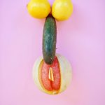 Artistic composition of fruits resembling abstract shapes on a vibrant pink surface.
