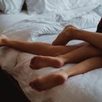 A close-up of intertwined legs illustrating intimacy and relaxation on a bed.