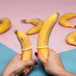 Creative display of bananas with condoms on pastel background, promoting safe sex.