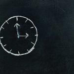 Chalk-drawn clock on a blackboard, symbolizing time and education concepts.